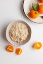 Homemade oatmeal porridge with tangerine or clementin fruits slices on a white background. Colorful fruit background Royalty Free Stock Photo