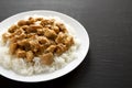Homemade Orange Chicken with White Rice on a white plate on a black background, side view. Copy space Royalty Free Stock Photo