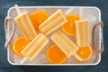 Homemade orange popsicles in a rustic ice tray