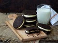 Homemade Oreo chocolate cookies with white marshmallow cream and glass of milk on dark background. Royalty Free Stock Photo