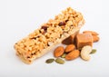 Homemade organic granola cereal bar with nuts and dried fruit on white background with oats and raw wheat. Royalty Free Stock Photo