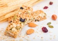 Homemade organic granola cereal bar with nuts and dried fruit on white background with oats and raw wheat. Royalty Free Stock Photo