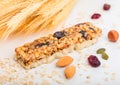 Homemade organic granola cereal bar with nuts and dried fruit on white background with oats and raw wheat. Royalty Free Stock Photo