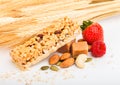 Homemade organic granola cereal bar with nuts and dried fruit on white background with oats and raw wheat. Strawberry and raspberr