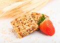 Homemade organic granola cereal bars with nuts and dried fruit on white background with oats and raw wheat and strawberry Royalty Free Stock Photo