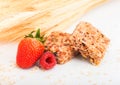 Homemade organic granola cereal bars with nuts and dried fruit on white background with oats and raw wheat. Strawberry and raspber Royalty Free Stock Photo