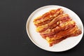 Homemade Oven Baked Bacon on a  Plate on a black background, side view. Space for text Royalty Free Stock Photo