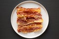 Homemade Oven Baked Bacon on a  Plate on a black background, top view. Flat lay, overhead, from above Royalty Free Stock Photo