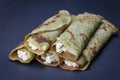 Homemade pancakes with green spirulina stuffed white cottage cheese with raisins on a black slate background, close up Royalty Free Stock Photo