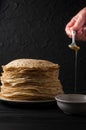 Homemade pancakes with honey and walnuts, vintage white plate, dipper, dark wooden table.