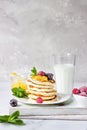 Homemade pancakes with jam, frozen raspberries, blackberries and mint and glass with milk on light grey background. Royalty Free Stock Photo