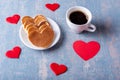 Homemade pancakes in the shape of a heart on a white plate, a mug with coffee or cocoa on a blue background