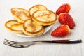 Pancakes in saucer, several strawberries, fork on table Royalty Free Stock Photo