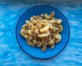 Homemade pasta breakfast with minced chicken, roasted with spices and tomato sauce on a ceramic blue plate, served on a blue Royalty Free Stock Photo