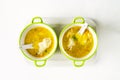 Homemade pasta chicken soup in light green bowls on a white tray on white background, top view