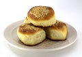 Homemade pastries, ruddy buns with sesame seeds on a pearl plate on a white background Royalty Free Stock Photo