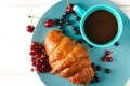 Homemade pastries. A ruddy croissant with berries lies on a bright plate next to a cup of coffee Royalty Free Stock Photo