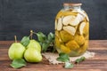 Homemade pear compote and fresh pears with leaves on dark wooden background
