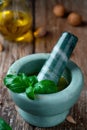 Homemade pesto sauce, prepared in a marble mortar. Ingredients on a wooden table, selective focus on basil leaves on a mortar, Royalty Free Stock Photo