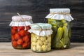 Homemade pickled cherry tomatoes, cucumbers, champignons, garlic, eggplant, red peppers in jars on wooden shelf Homemade canned Royalty Free Stock Photo
