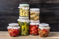 Homemade pickled cherry tomatoes, cucumbers, champignons, garlic, eggplant, red peppers in jars on wooden shelf Homemade canned Royalty Free Stock Photo