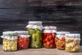 Homemade pickled cherry tomatoes, cucumbers, champignons, garlic, eggplant, red peppers in jars on wooden shelf Homemade canned Royalty Free Stock Photo