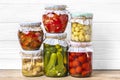 Homemade pickled cherry tomatoes, cucumbers, champignons, garlic, eggplant, red peppers in jars on wooden shelf Homemade canned Royalty Free Stock Photo