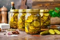 Homemade Pickled Cucumbers in Glass Jars with Spices and Seasonings on Rustic Wooden Background