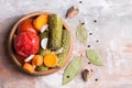 Homemade pickled tomatoes and cucumbers with carrots, garlic and Bay leaf, on a blurred light background. Flat lay.