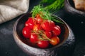 Homemade pickled tomatoes served in the dark bowl and decorated with dill