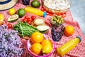 Homemade picnic with fresh fruits, vegetables, salad, orange juice, flowers and baguette on a red plaid. Beautiful still life