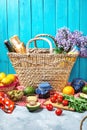 Homemade picnic with fruits, vegetables, salad, orange juice, flowers and baguette in wicker basket. Beautiful still life