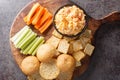 Homemade Pimento Cheese Dip with carrots, celery and crackers, side view closeup on the wooden board. Horizontal top view