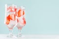 Homemade pink lemonade with strawberry slices, ice cubes, soda in two misted glasses on white wood table, pastel green color. Royalty Free Stock Photo