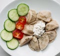 Homemade pirogi dish with different fillings, tomato and cucumber.