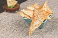 Homemade pita chips in turquoise square bowl on rustic fabric napkin. Red dip sauce in the background. Cooked without oil Royalty Free Stock Photo