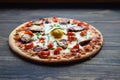 Homemade pizza with cheese ,salami,tomato and egg. Pizza on a wooden cutting board