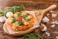 A lovely little delicious pizza on a beautiful wooden plaque for filing on a wooden table. Homemade pizza with cheese and vegetabl