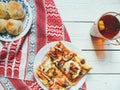 homemade pizza, a cup of tea with lemon and bread rolls on a white table