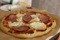 Homemade pizza with ham and cheese lies on parchment close-up view super on the side. Homemade fast food background Royalty Free Stock Photo