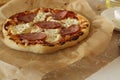 Homemade pizza with ham and cheese lies on parchment close-up view super on the side. Homemade fast food background Royalty Free Stock Photo