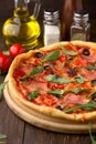 Homemade pizza with ham, tomatoes and herbs on dark wooden table. Royalty Free Stock Photo