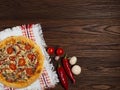 Homemade pizza with minced meat, red pepper, mushrooms and tomatoes lies on a natural wooden surface. Royalty Free Stock Photo