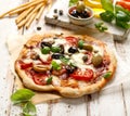 Homemade pizza with tomatoes, olives, salami, mozzarella cheese and fresh basil on a wooden rustic table Royalty Free Stock Photo