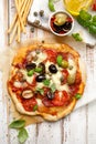 Homemade pizza with tomatoes, olives, salami, mozzarella cheese and fresh basil on a wooden rustic table Royalty Free Stock Photo