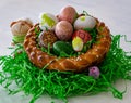 A homemade and plaited Easter nest made from yeast dough with colorful easter eggs and little chicks.