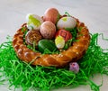 A homemade and plaited Easter nest made from yeast dough with colorful easter eggs and little chicks.