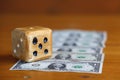 A homemade play cube lays on a track of dollar bills and symbolizes the volatility of financial markets