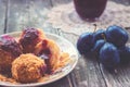 Plum dumplings, plums and plum sauce on wooden background