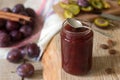 Homemade plum jam or confiture in a glass jar, and fresh plums on a wooden background. Rustic style, selective focus. Royalty Free Stock Photo
